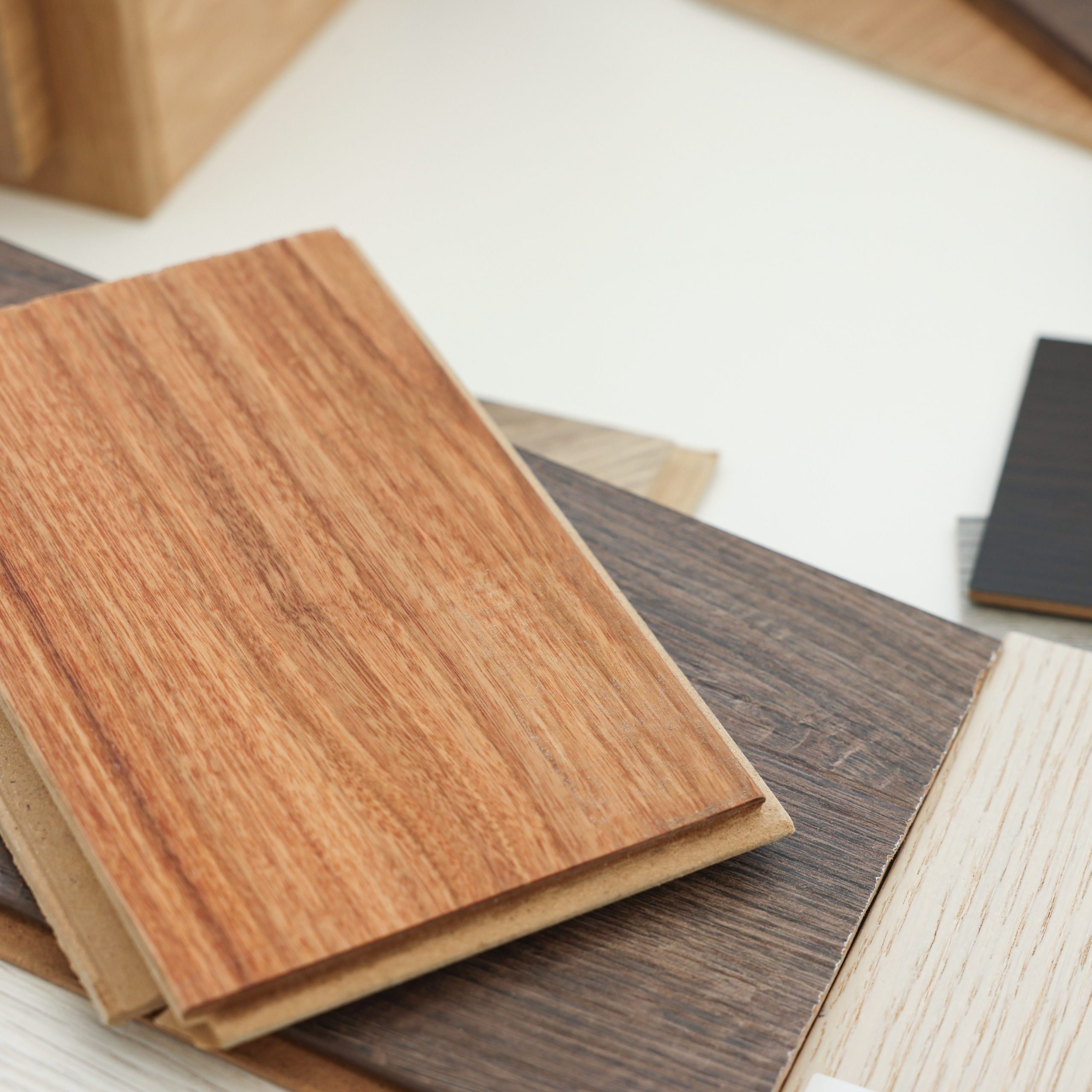 Different samples of wooden flooring on white table, closeup